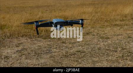 DJI Mavic 2 Pro drone flying low over parched grass Stock Photo