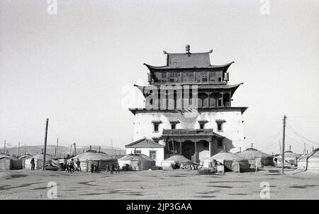1960s, historical, exterior view of old Buddhist temple, the Janraiseg Temple at the Gandan Monastery in Ulaanbaatar, Mongolia, Central Asia. At ground level, a number of traditional nomadic, low-level dwellings known as yurts. The yurt is a distinctive part of the Mongolian national identity. Stock Photo