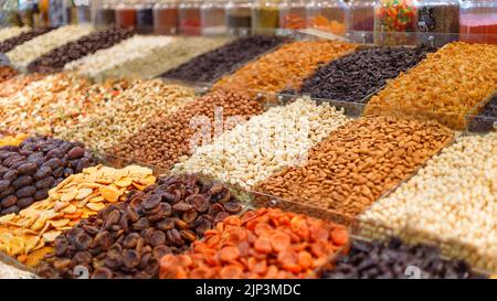 Stalls with nuts and dried fruits in the market close up with selective focus. Bright colored nuts and dried fruits on transparent trays Stock Photo