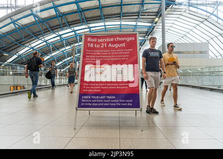 Waterloo London, UK. 15 August 2022 . A sign announcing strike action at a busy Waterloo station with commuters on Monday morning. The Rail, Maritime and Transport Workers (RMT) union has announced strike action from Thursday 18- 21 August  in a walkout by train drivers over a dispute demanding an increase in pay in line with the current inflation of 15 per cent  Passengers have been advised not to travel due to the  severe disruption  on those days Credit. amer ghazzal/Alamy Live News Stock Photo