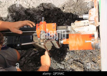 Worker drills a core hole in a house wall Stock Photo