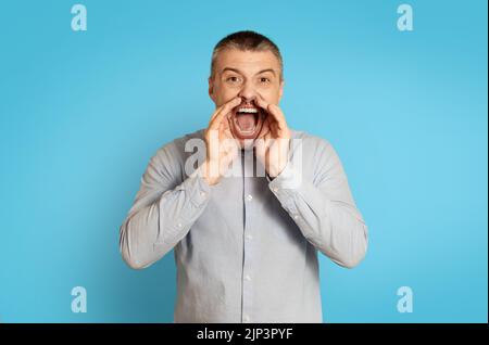 Emotional Middle Aged Man Shouting Announcing Offer Over Blue Background Stock Photo