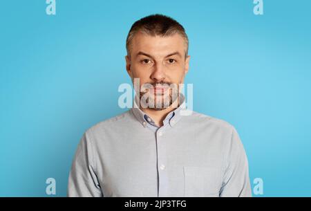 Portrait Of Serious Middle Aged Man Posing Over Blue Background Stock Photo