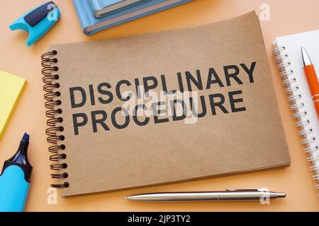 Notebook about disciplinary procedure with papers on the table. Stock Photo