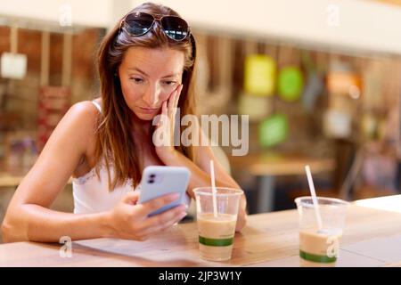 Woman looking shocked looking at message Stock Photo