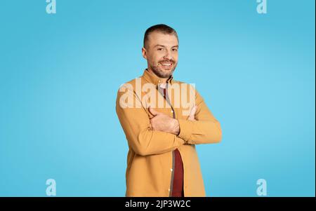 Mature Man Posing Crossing Hands Standing On Blue Studio Background Stock Photo