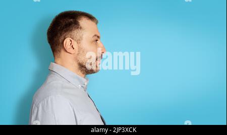 Serious Middle Aged Man Looking Aside, Blue Background, Side View Stock Photo