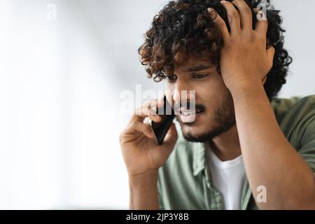 Worried eastern man having phone conversation, closeup Stock Photo
