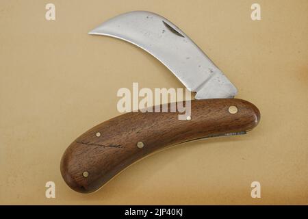 folding pruning knife with curved long blade on vintage paper background Stock Photo
