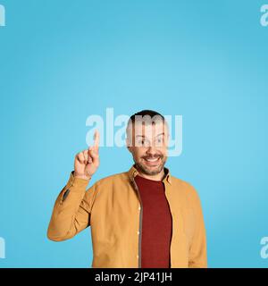 Middle Aged Male Pointing Finger Up Having Idea, Blue Background Stock Photo
