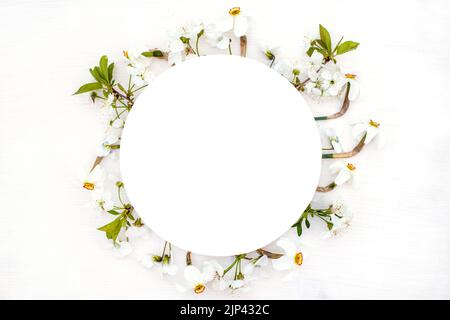 Round frame with spring flowers. fresh cherry blossoms, violets and white daffodils in the form of wreath on wooden background. Stock Photo