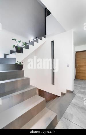 facade of a modern house with stone, staple that wraps the windows painted in gray, metal entrance, ironwork Stock Photo