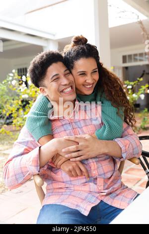 Happy biracial couple on garden terrace embracing outside house smiling Stock Photo