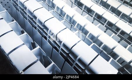 Many white aluminum or bimetal heating radiators stand next to each other on a stand in a store Stock Photo