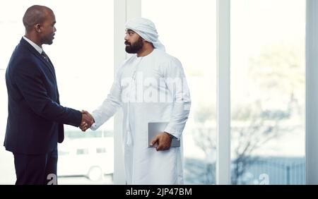 Heres to making business even better. two businessmen shaking hands in a modern office. Stock Photo