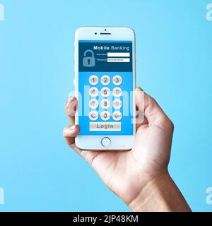 Pay your accounts on your cellphone. Studio shot of an unrecognizable woman holding a cellphone displaying an internet banking webpage against a blue Stock Photo