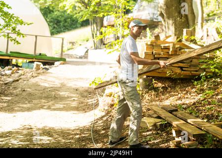 Young manual worker standing at stack with thin wooden boards during his work at furniture factory Stock Photo