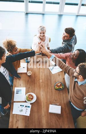 Diverse group of businesspeople high five after planning a meeting in an office. Above ambitious happy confident professional team of colleagues Stock Photo