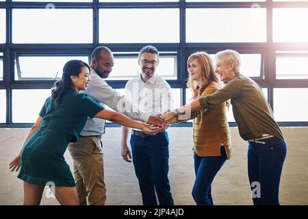 Teamwork, fun and collaboration by diverse team joining hands in team building. Excited group linking, joining and supporting goal, mission or vision Stock Photo