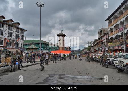 Srinagar, India. 15th Aug, 2022. Indian tourists unfurl the Indian Flag in presence of army personnel in Srinagar's Lalchowk, Indian administered Kashmir on 15 August 2022. (Photo: Hassnain Riza/Sipa USA) Credit: Sipa USA/Alamy Live News Stock Photo