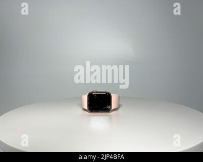 Orlando, FL USA - August 4, 2022: A rose gold Apple Watch with a pink band and cracked screen. Stock Photo