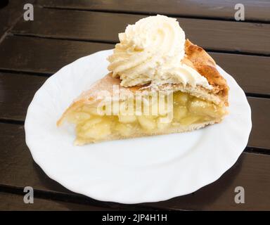 A slice of apple pie with cream on a white plate. Stock Photo