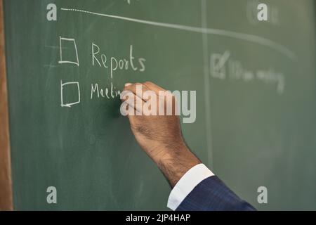 Business man writing work plan checklist on blackboard. Close up Stock Photo