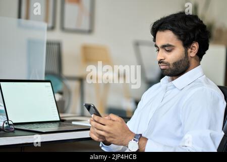 Indian business man employee using smartphone texting at work. Stock Photo