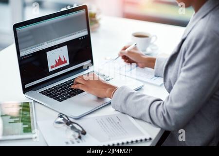 Female project manager typing on laptop looking at charts, analyzing statistics. Financial data analyst or business woman looking at KPI bar graph Stock Photo