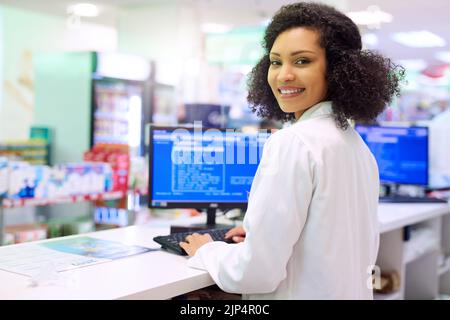 Would you like a receipt. a pharmacist working on a computer in a pharmacy. Stock Photo