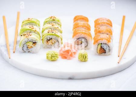 Sushi rolls on platter, bright background. Served with wasabi and ginger. Assorted Japanese sushi. Traditional food. Stock Photo