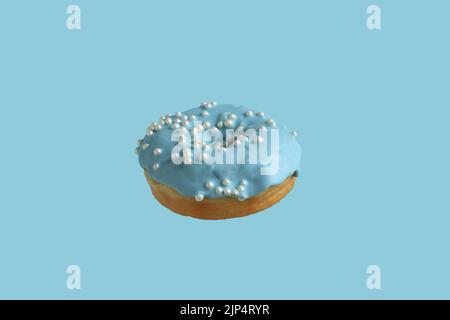 Donuts covered with pale blue icing and sprinkled with pearl sugar beads on a light blue background. Closeup. Stock Photo