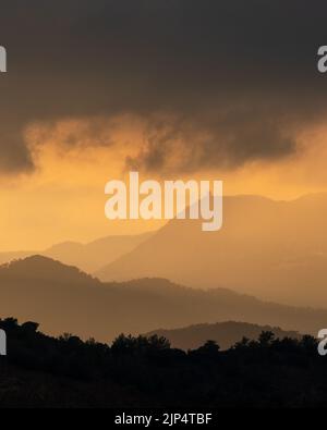 Sunset with stormy cloud sky and dramatic orange sunlight above mountain Troodos mountains Cyprus Stock Photo