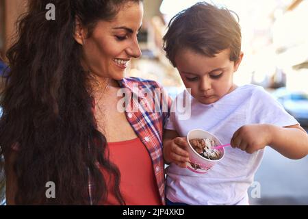 Tell me how it tastes. an attractive young woman and her young son at an ice cream shop. Stock Photo