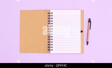Open notebook with pencil on pastel purple background. Flat lay copy space Stock Photo