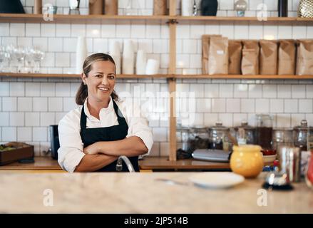 Business owner, barista standing with arms crossed, looking confident and proud while working at a restaurant. Cafe worker, employee and entrepreneur Stock Photo