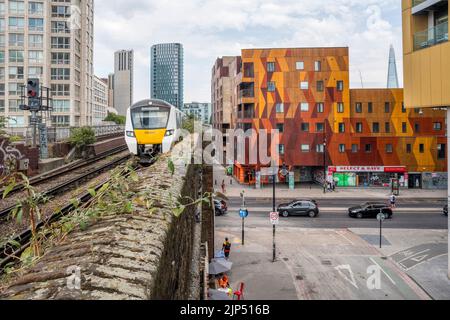 A Thameslink train entering Elephant & Castle railway station, travelling south from central London.  Colourful Arch Street housing in background. Stock Photo