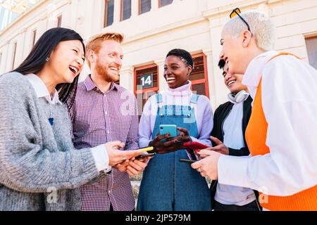Young adults with mobile phones laughing and having fun outdoors. Stock Photo