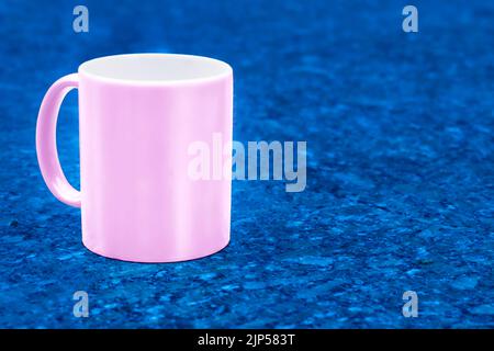 Pink ceramic cup mug on dark blue emerald spotted background Stock Photo