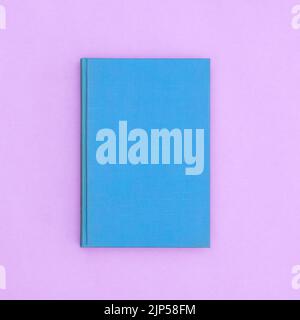 Blue hardcover vintage book on pastel purple background. Flat lay copy space Stock Photo