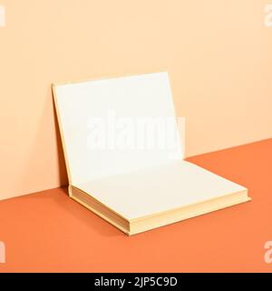 Creative backgorund with open hardcover book on two shade orange background. Flat lay copy space Stock Photo