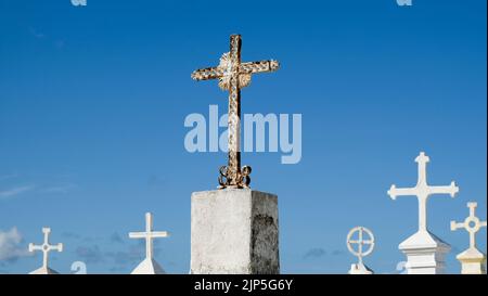 A group of metal grave crosses on stone pedestals with blue sky in the background, religious and Spiritual theme. Stock Photo