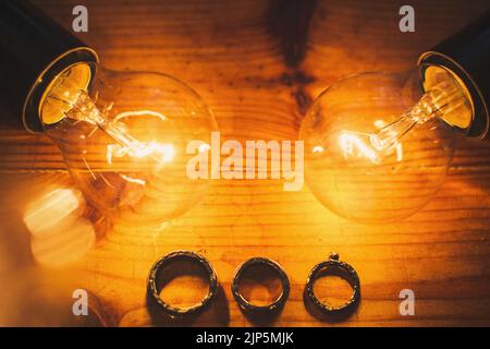 Three wedding rings and two light bulbs on the table. Stock Photo