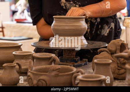 A potter man working on a potter's wheel making a ceramic pot out of clay. Master class on modeling on a potter's wheel. Stock Photo