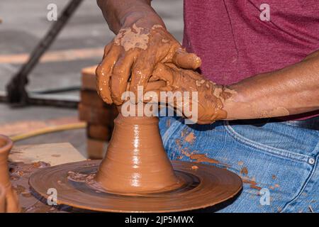 Hands 0f a potter man working on a potter's wheel making a ceramic pot out of clay. Master class on modeling on a potter's wheel. Stock Photo