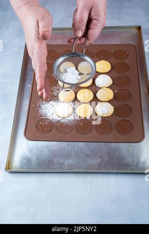 Confectioner sprinkling sugar over wedding sweet treats on a brown silicone plate. Stock Photo