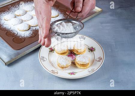 Confectioner using a steel sieve to sprinkle sugar on wedding sweet treat. Stock Photo