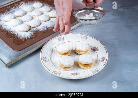 Confectioner using a steel sieve to sprinkle sugar on wedding sweet treat side view. Stock Photo