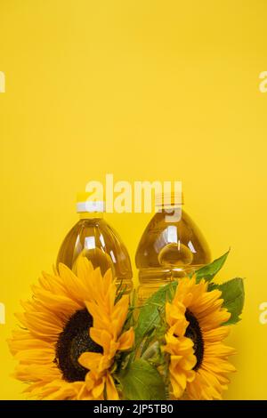 Oil bottles and sunflowers blooming on a yellow background.Organic natural farm sunflower oil. Edible oils. copy space Stock Photo