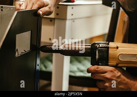 Male worker uses electric riveting gun. Hand holding riveting machine ...